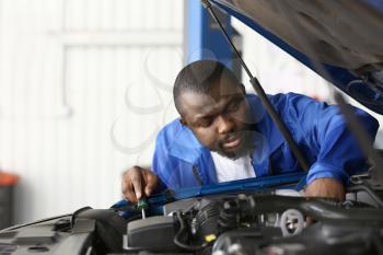 African-American mechanic working in car service center�