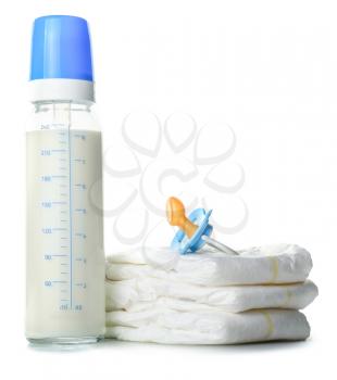 Bottle of milk for baby with pacifier and diapers on white background�