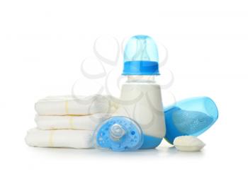 Bottle of baby milk formula with pacifier, diapers and nibbler on white background�