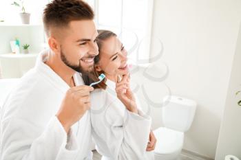 Young couple brushing teeth in bathroom�