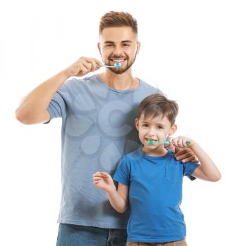 Portrait of father and his little son brushing teeth on white background�