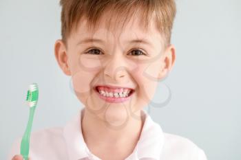 Portrait of little boy with toothbrush on light background�