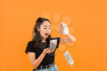 Asian woman throwing money against color background�