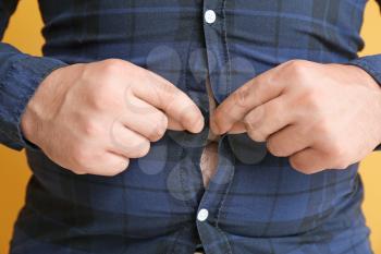 Overweight man putting on tight clothes, closeup. Weight loss concept�