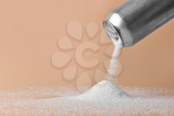 Sprinkling of sugar from tin can onto color background�