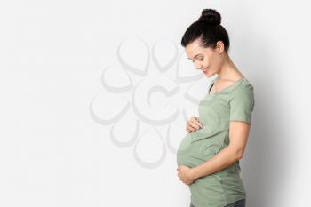 Beautiful young pregnant woman on light background�