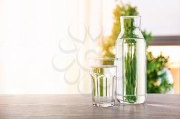 Glass and bottle of fresh water on table indoors�