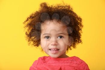 Portrait of little African-American girl on color background�