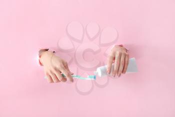 Female hands with toothbrush and paste on color background�