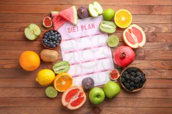 Different healthy food with diet plan on wooden table�