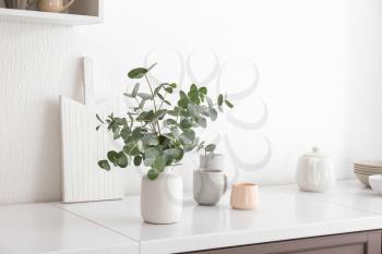 Vase with eucalyptus branches on table in kitchen�