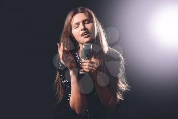 Beautiful young female singer with microphone on stage�