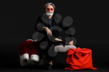 Portrait of stylish Santa Claus with gifts on dark background�
