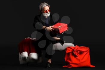 Portrait of stylish Santa Claus with gifts on dark background�