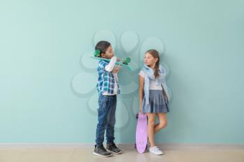 Cute fashionable children with skateboards near color wall�