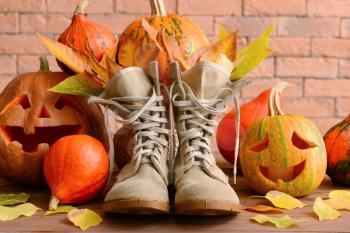 Boots, Halloween pumpkins and autumn leaves near brick wall�