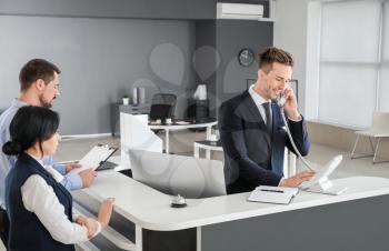 Male receptionist talking on phone in office�