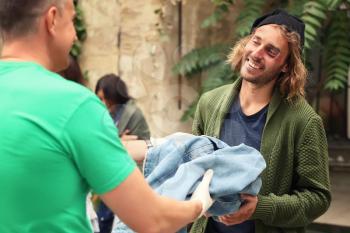 Volunteers giving clothes to homeless people outdoors�