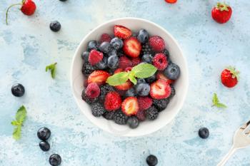 Bowl with tasty berry salad on color background�