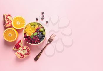 Bowl with tasty fruit salad on color background�