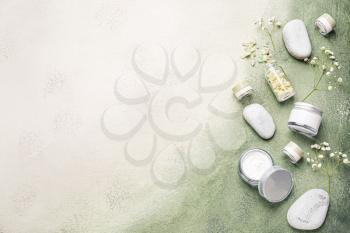 Cosmetic cream with spa items on color background�