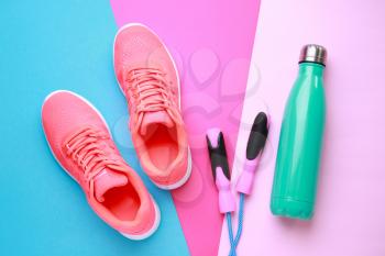 Sports water bottle, shoes and jumping rope on color background�