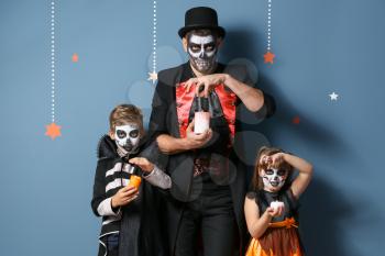 Father with children in Halloween costumes and with candles on color background�