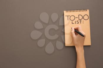 Woman making to-do list on grey background�