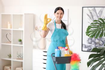 Female janitor with cleaning supplies in room�