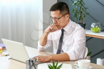 Asian businessman working on laptop in office�