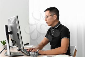 Asian programmer working on computer in office�
