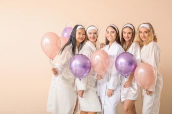Beautiful young women in bathrobes and with air balloons on light background�