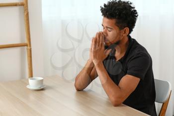 Young African-American man praying at home�