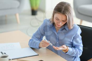 Diabetic woman checking blood sugar level in office�