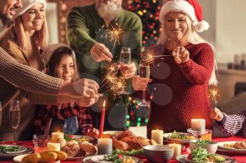 Happy family with Christmas sparklers and glasses of champagne at home�