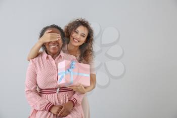 Portrait of African-American woman greeting her mother on light background�