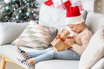 Cute little girl with Christmas gift at home�