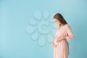 Beautiful pregnant woman on color background�