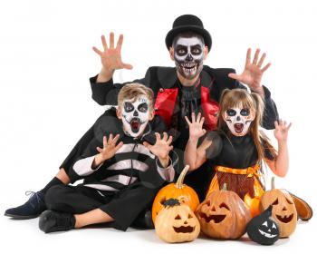 Father with children in Halloween costumes and with pumpkins on white background�