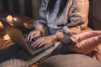 Woman with laptop sitting on floor at night�