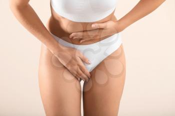 Young woman suffering from abdominal pain on light background. Gynecology concept�