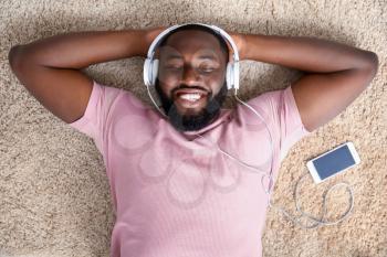 African-American man listening to music at home, top view�