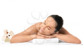 Beautiful woman with spa supplies lying on towel against white background�
