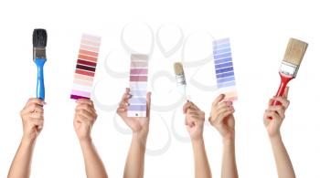 Female hands with paint brushes and color samples on white background�