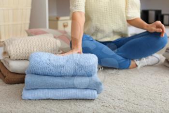 Woman with stacks of clean clothes at home�
