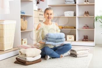 Woman with stacks of clean clothes at home�