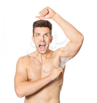 Screaming young man epilating armpits on white background�