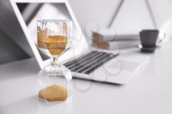 Hourglass and laptop on table in room�