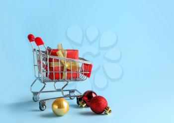 Small shopping cart with gift box on color background�