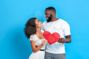 Portrait of happy African-American couple with red heart on color background�